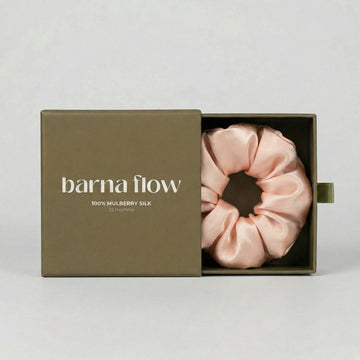 Pink silk scrunchie in a 'barna flow' box on a light gray background