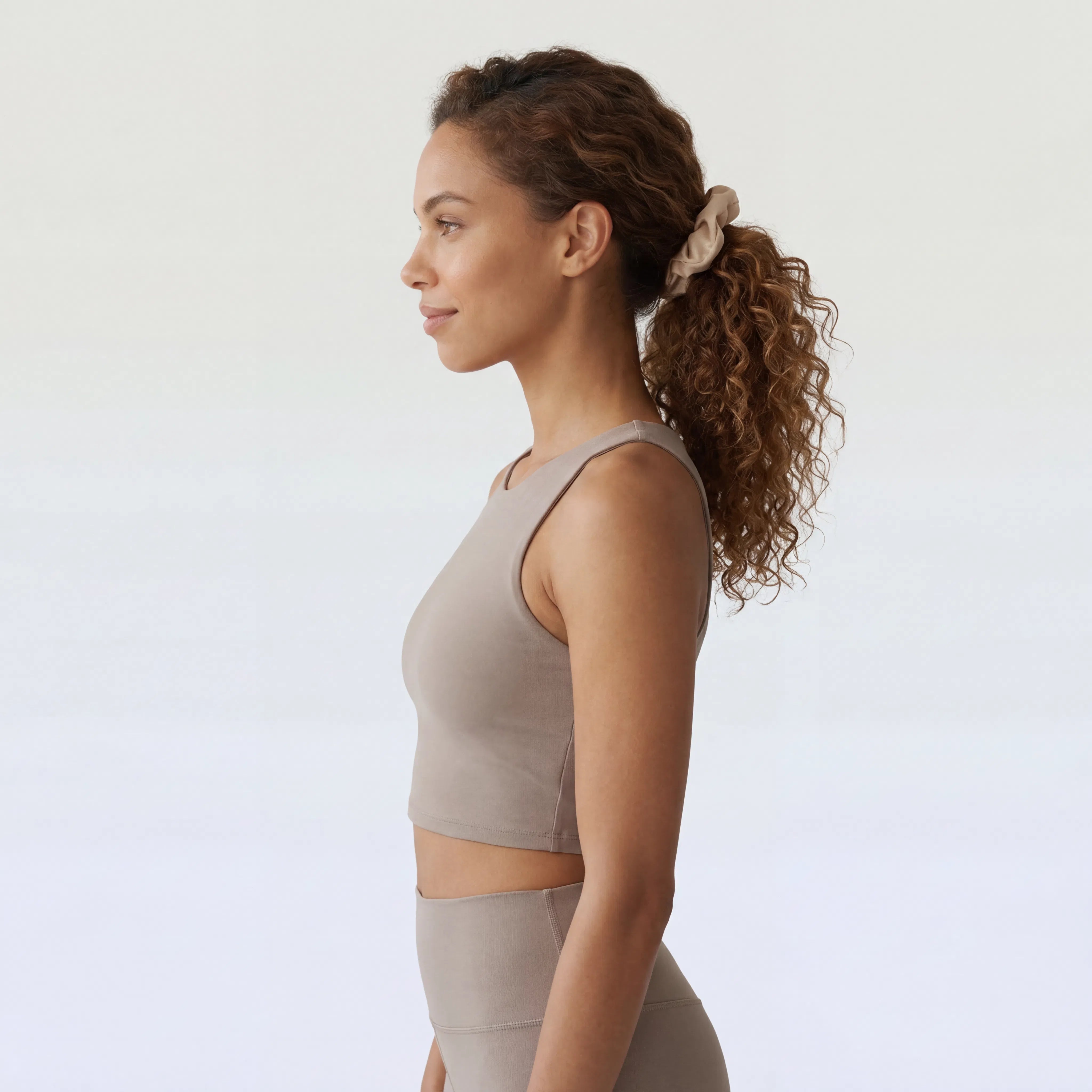 Woman wearing a beige athletic outfit against a white background