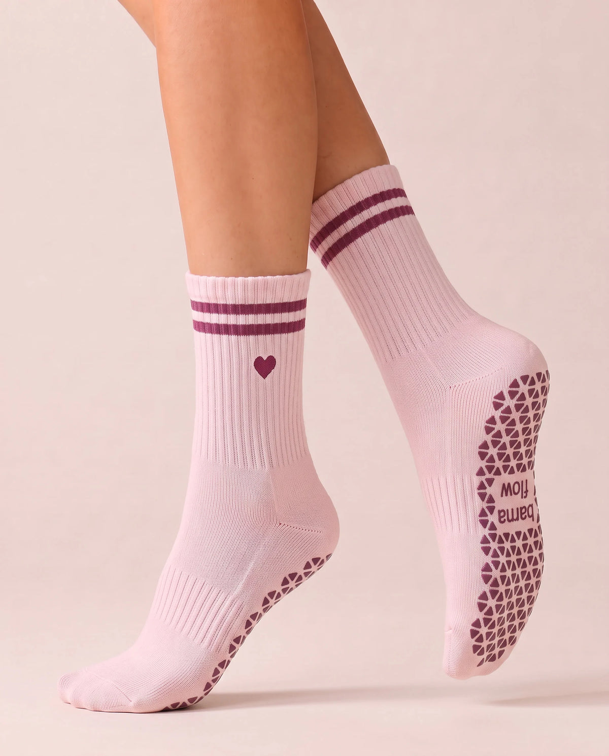 Calcetines antideslizantes Hearts & Stripes en pleno paso, con el agarre exterior color frambuesa a la vista